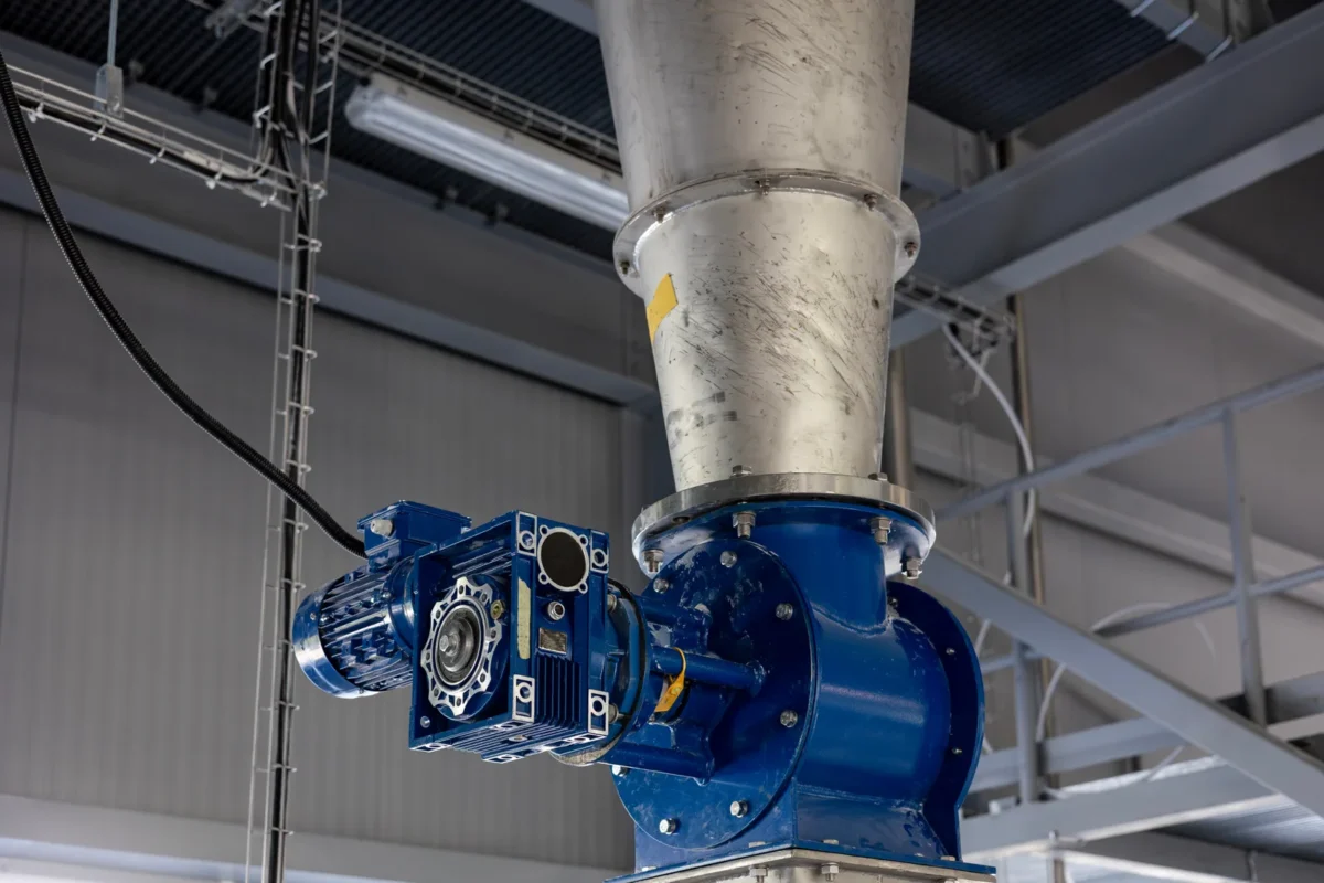 Blue rotary discharge valve beneath a stainless-steel powder hopper.