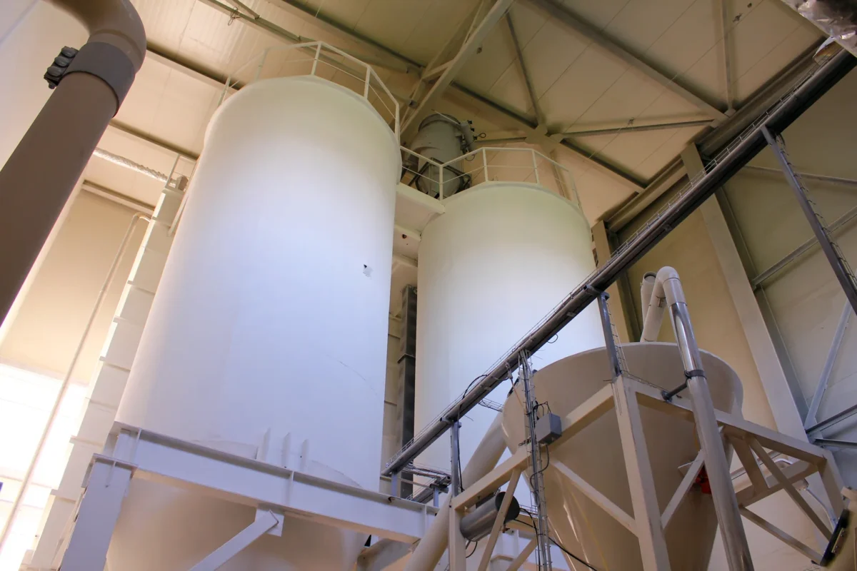 White ingredient vessels and transfer equipment inside a flour mill.