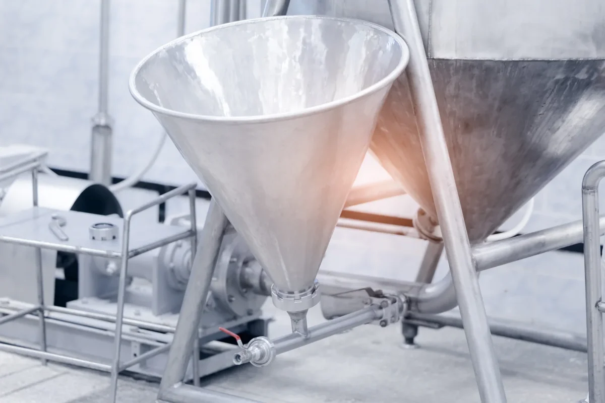 Metal ingredient hoppers and their discharge connections inside a food processing plant.