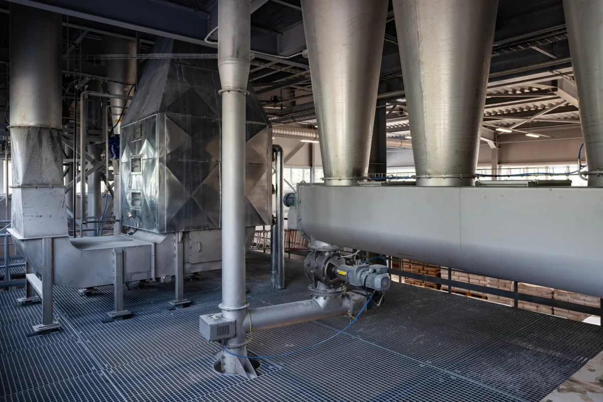 Metal powder hoppers and a screw conveyor inside an industrial production building.